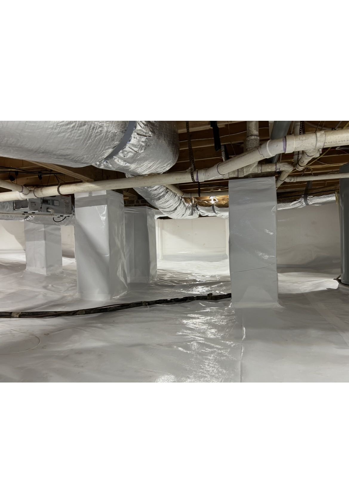 View of a sealed crawlspace interior with white vapor barrier lining the floor and support structure